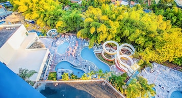 Vista aérea de um resort com várias piscinas, toboáguas e vegetação exuberante.