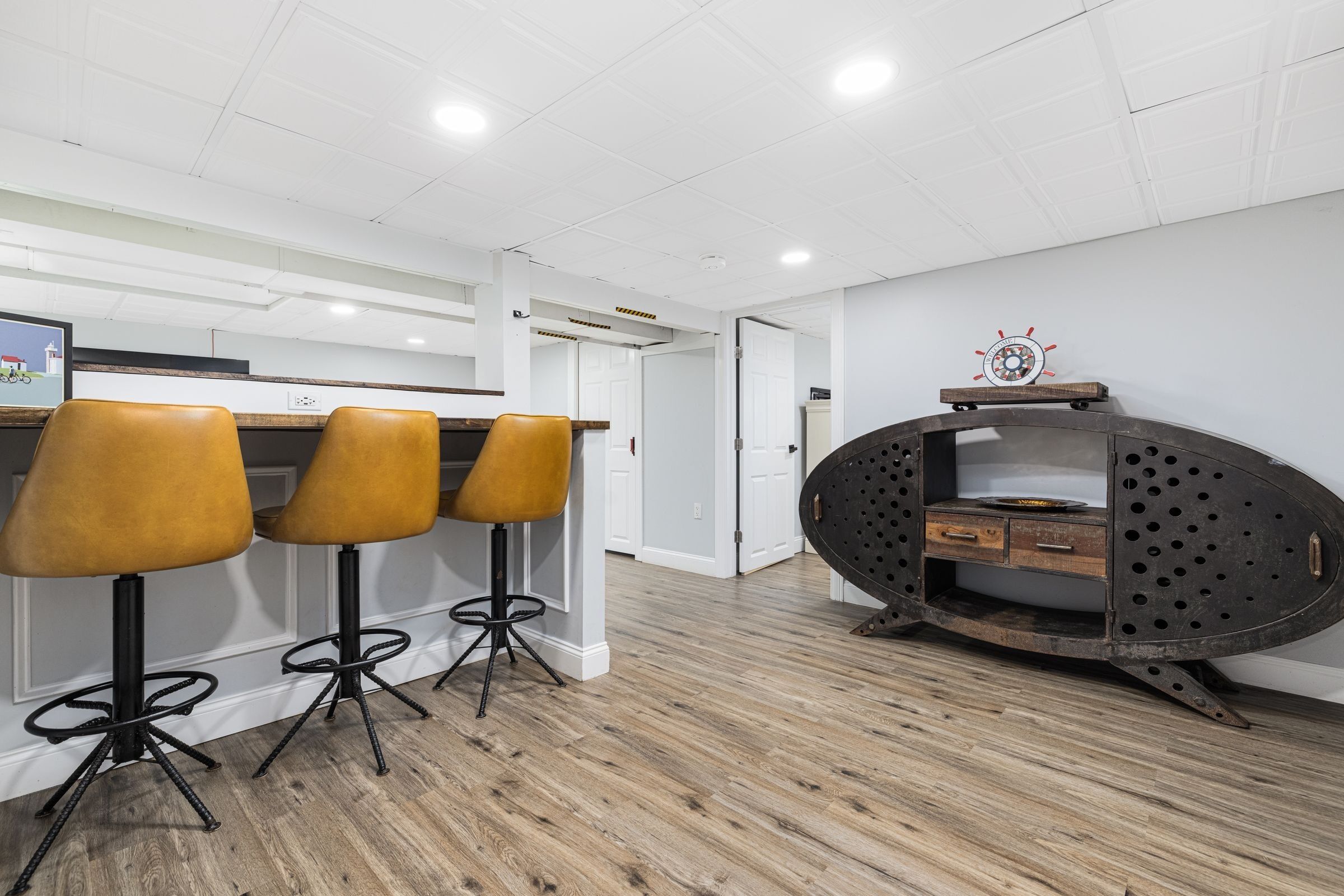 Une cuisine moderne avec un plancher en bois, un coin bar avec des tabourets et un meuble métallique original.