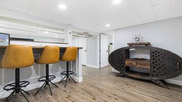 Une cuisine moderne avec un plancher en bois, un coin bar avec des tabourets et un meuble métallique original.