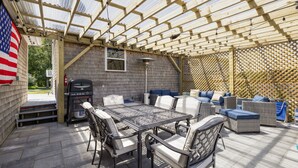 An outdoor patio with a covered seating area, a grill, and a flag. - 4br & 2ba Ranch style house w/ huge backyard! (PORTSMOUTH)