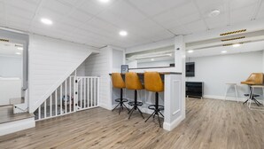 A modern interior with a staircase, wooden flooring, and a bar area with stools. - 4br & 2ba Ranch style house w/ huge backyard! (PORTSMOUTH)