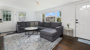 A modern living room with a gray sectional sofa, a round coffee table, and a patterned rug. - 4br & 2ba Ranch style house w/ huge backyard! (PORTSMOUTH)