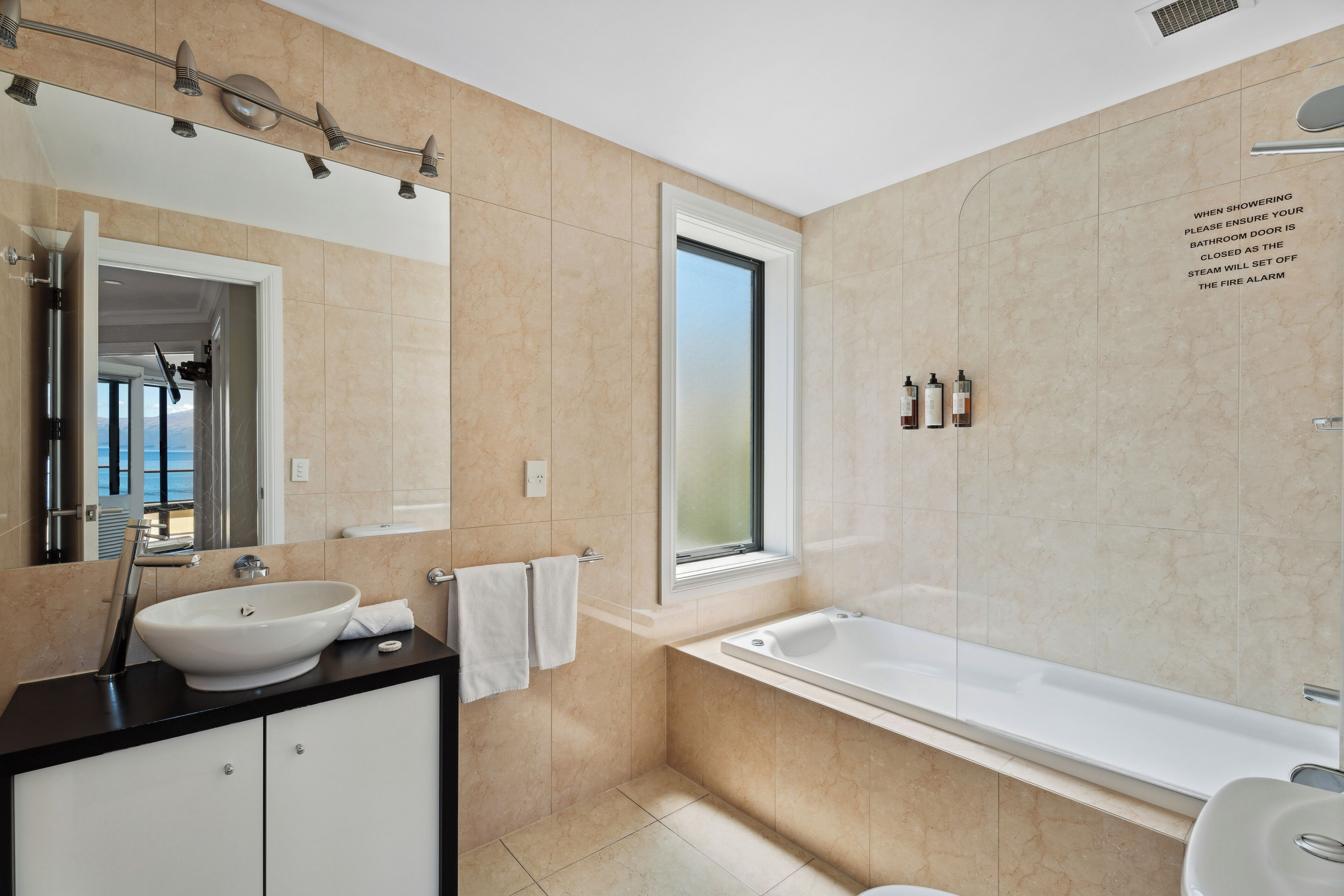 A modern bathroom with a large bathtub, a sink, and a window.