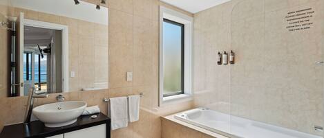 A modern bathroom with a large bathtub, a sink, and a window.
