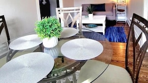 A dining area with a glass table and chairs, a potted plant, and a sofa in the background. - Dallas Fair Park 3B/2B Downtown Deep Ellum (Dallas)