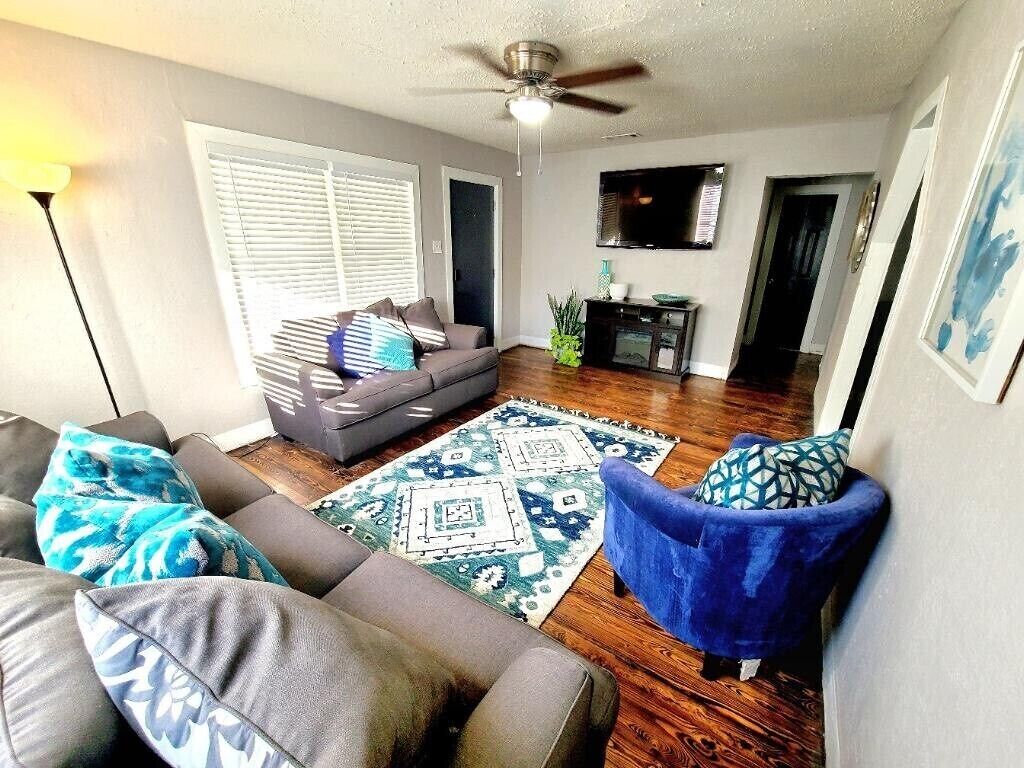 Ein Wohnzimmer mit grauem Sofa, blauem Sessel und einem gemusterten Teppich.