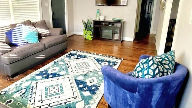A living room with a gray sofa, a blue armchair, and a patterned rug. - Dallas Fair Park 3B/2B Downtown Deep Ellum (Dallas)