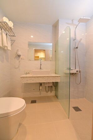A modern bathroom with a glass-enclosed shower, a white sink, and a toilet. - T Shine Resort and Spa (Lapu-Lapu)