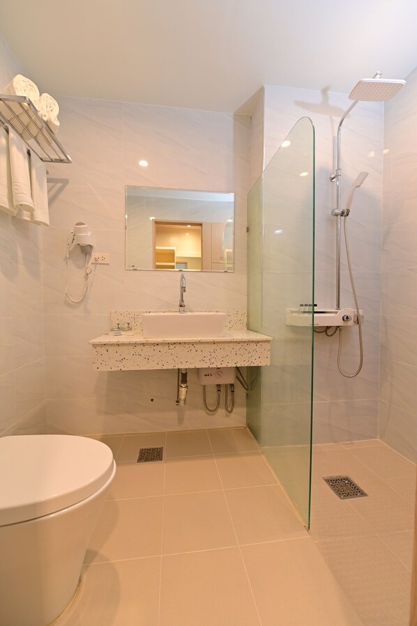 Une salle de bain moderne avec une douche à parois de verre, un lavabo blanc et des toilettes.