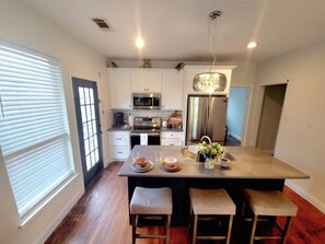 A modern kitchen with white cabinetry, stainless steel appliances, and a central island with stools. - Dallas Downtown 3B/2B Uptown Deep Ellum Greenville (Dallas)