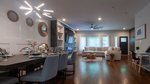 A modern living room with a dining area, wooden flooring, and a ceiling fan. - Five75 Lux ATL King Bed & Game Room Downtown (Atlanta)