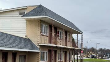 Un motel à deux étages doté d’un balcon au deuxième étage, d’un espace de stationnement couvert et donnant sur la rue.