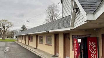 A motel with a Coca-Cola vending machine, a covered walkway, and a parking lot.