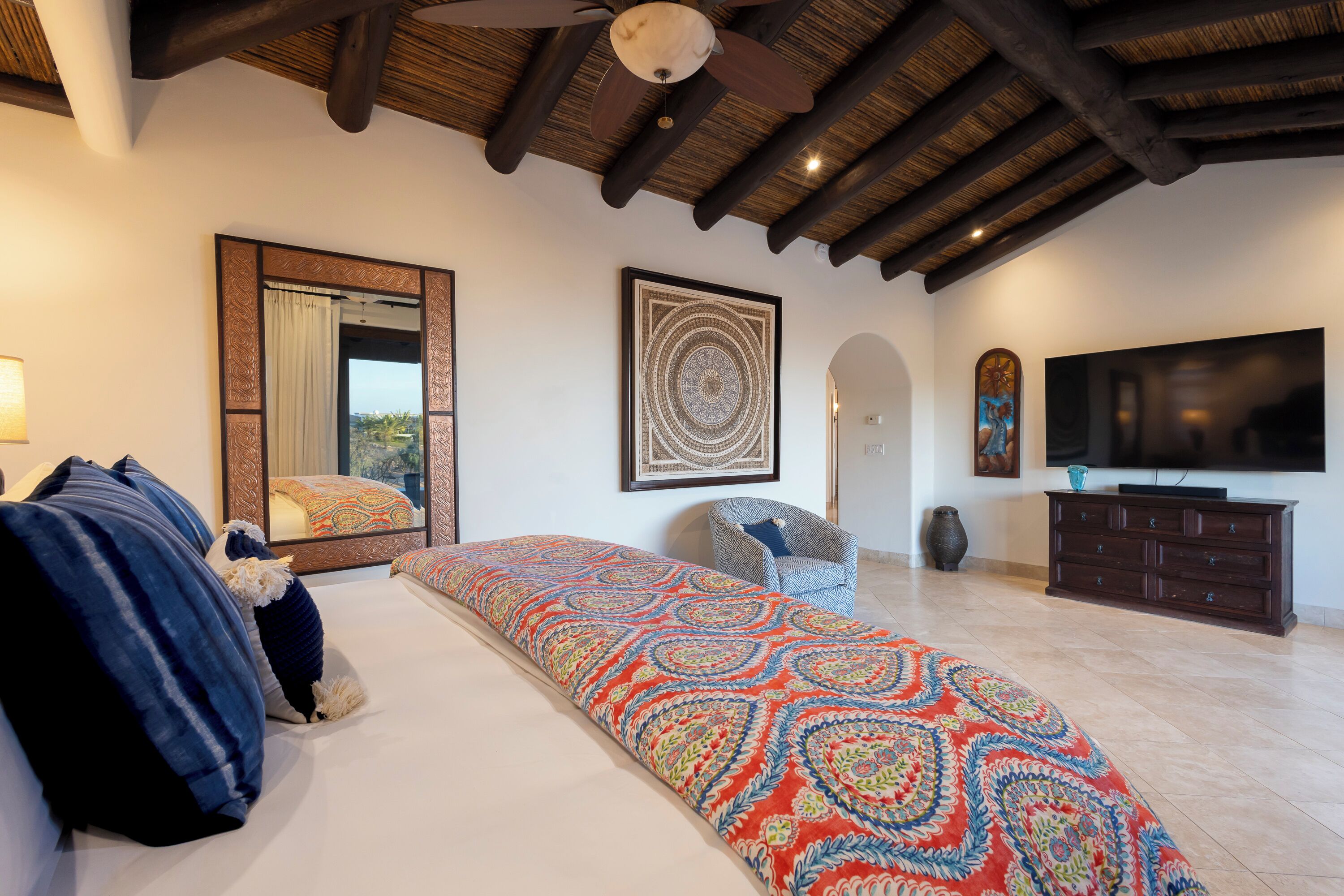 A bedroom with a large bed, a television, and a ceiling fan.