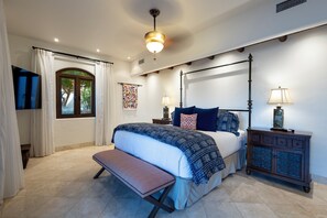 A bedroom with a four-poster bed, a bench, a nightstand, and a cabinet.
