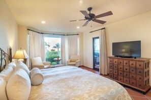 A hotel room with a bed, a television on a wooden cabinet, and a ceiling fan.