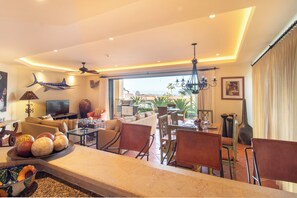 A spacious living area with a large dining table, comfortable seating, a television, and a view of the outdoors.
