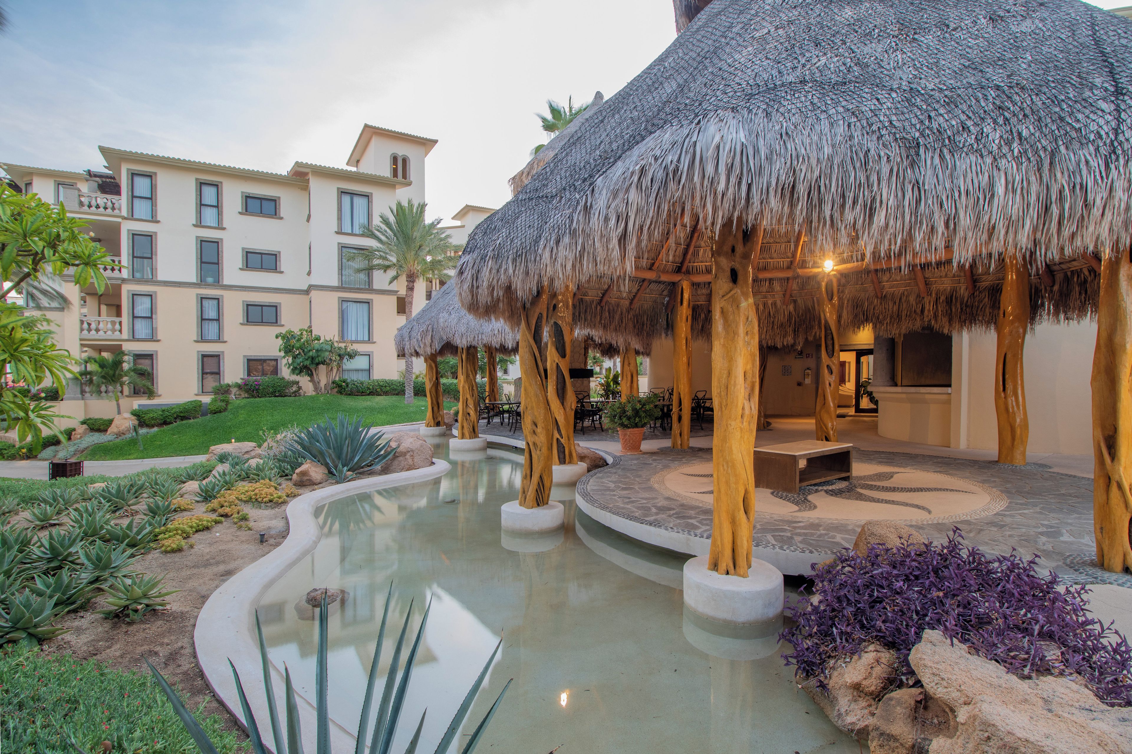 A resort with a pool, thatched-roof structures, and a building with multiple balconies.