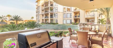 Um pátio com uma churrasqueira Weber Genesis Gold, móveis de exterior e vista para um edifício com varandas.