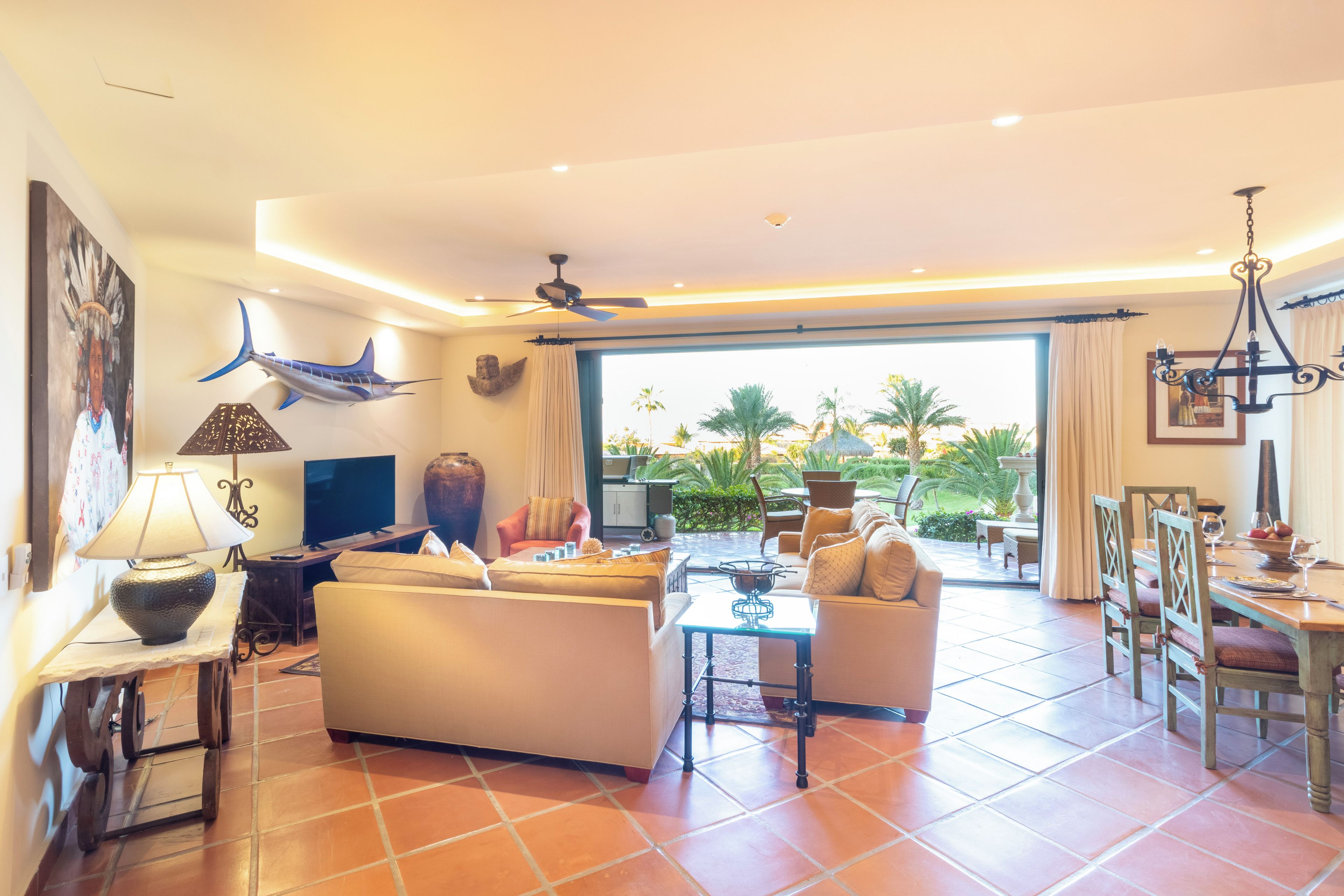 A spacious living area with a sofa, TV, and a dining table set for four.