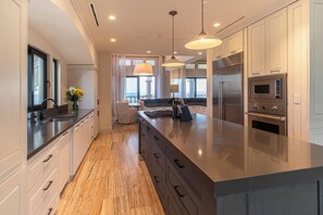 A modern kitchen with a large island, stainless steel appliances, and a view to the outside.