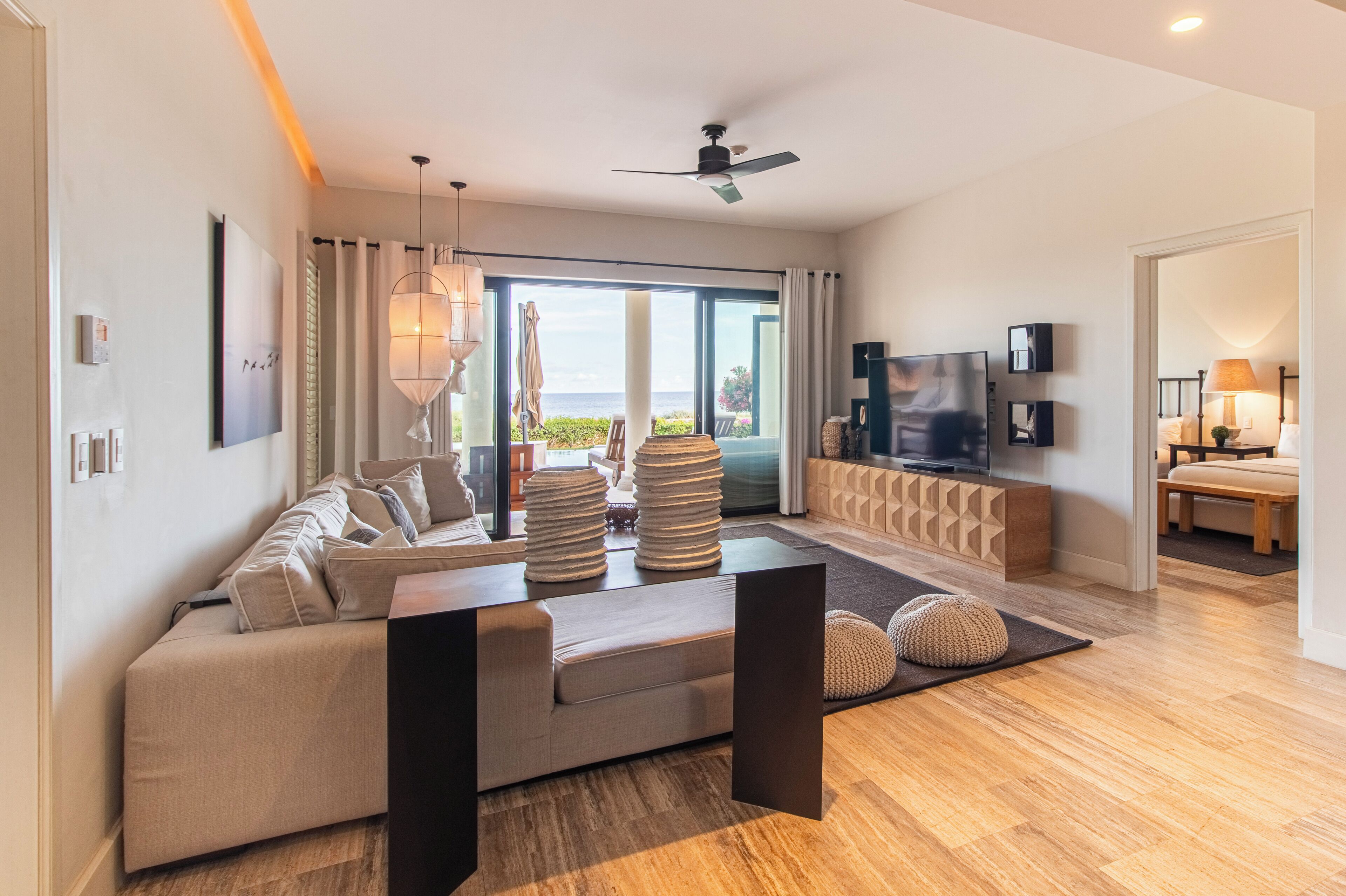 A modern living room with a sofa, coffee table, TV, and a view of the ocean.