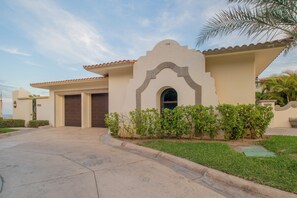 A residential building with a stucco exterior, a tiled roof, and a front entrance with a door and window. - Villa Perdiz, Puerta del Sol | 4 Bed, 4 Bath (Cabo San Lucas)