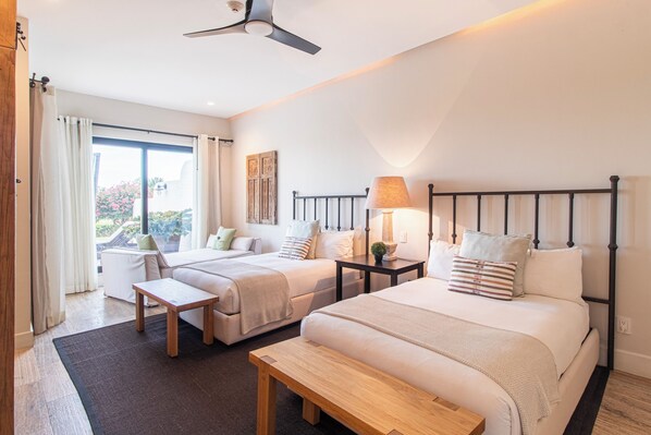 A hotel room with two beds, a bench, a table, and a ceiling fan. - Villa Perdiz, Puerta del Sol | 4 Bed, 4 Bath (Cabo San Lucas)