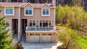 A two-story house with a stone staircase, a garage, and a balcony.