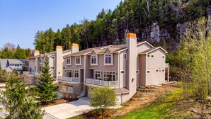 A multi-story residential building with a stone foundation, multiple chimneys, and a balcony.