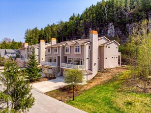 Ein mehrgeschossiges Wohngebäude mit Steinfundament, mehreren Schornsteinen und einem Balkon.