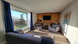 A living room with a sofa, two armchairs, a coffee table, and a fireplace. - Lovely Three Bedroom Farmhouse between Lethbridge and Coaldale (Coaldale)