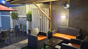 An outdoor seating area with wicker furniture, a glass table, and a red umbrella. - The Leneade - Mobo Apt. 6 at City Centre/Wuse 2 (Abuja)