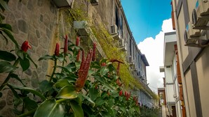 Une rue étroite, bordée d’un côté par un mur de pierre et de l’autre par un immeuble équipé de climatiseurs.