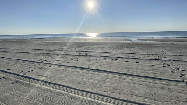 Une plage parsemée d'empreintes et baignée de soleil.