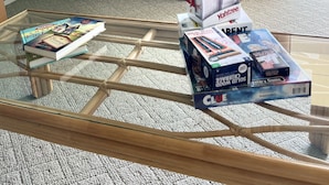 Une pièce comprenant une table basse en verre, une table d’appoint en bois agrémentée d’objets décoratifs et des boîtes de rangement.