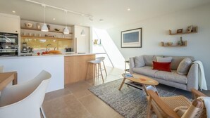 Una cocina moderna con una isla central, un comedor con sillas, un sofá y una pequeña mesa.