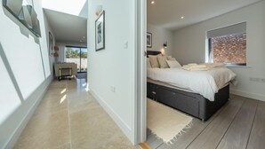Un dormitorio moderno con una cama grande, un escritorio pequeño y vistas al exterior.