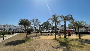 A park with playground equipment, trees, and a clear sky.