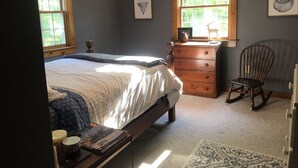Ein Schlafzimmer mit Bett, Schminktisch, Stuhl und einem Fenster mit Dekoration mit einem Reh.