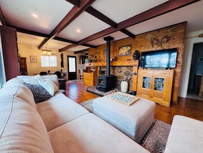A cozy living room with a sofa, ottoman, and a fireplace.