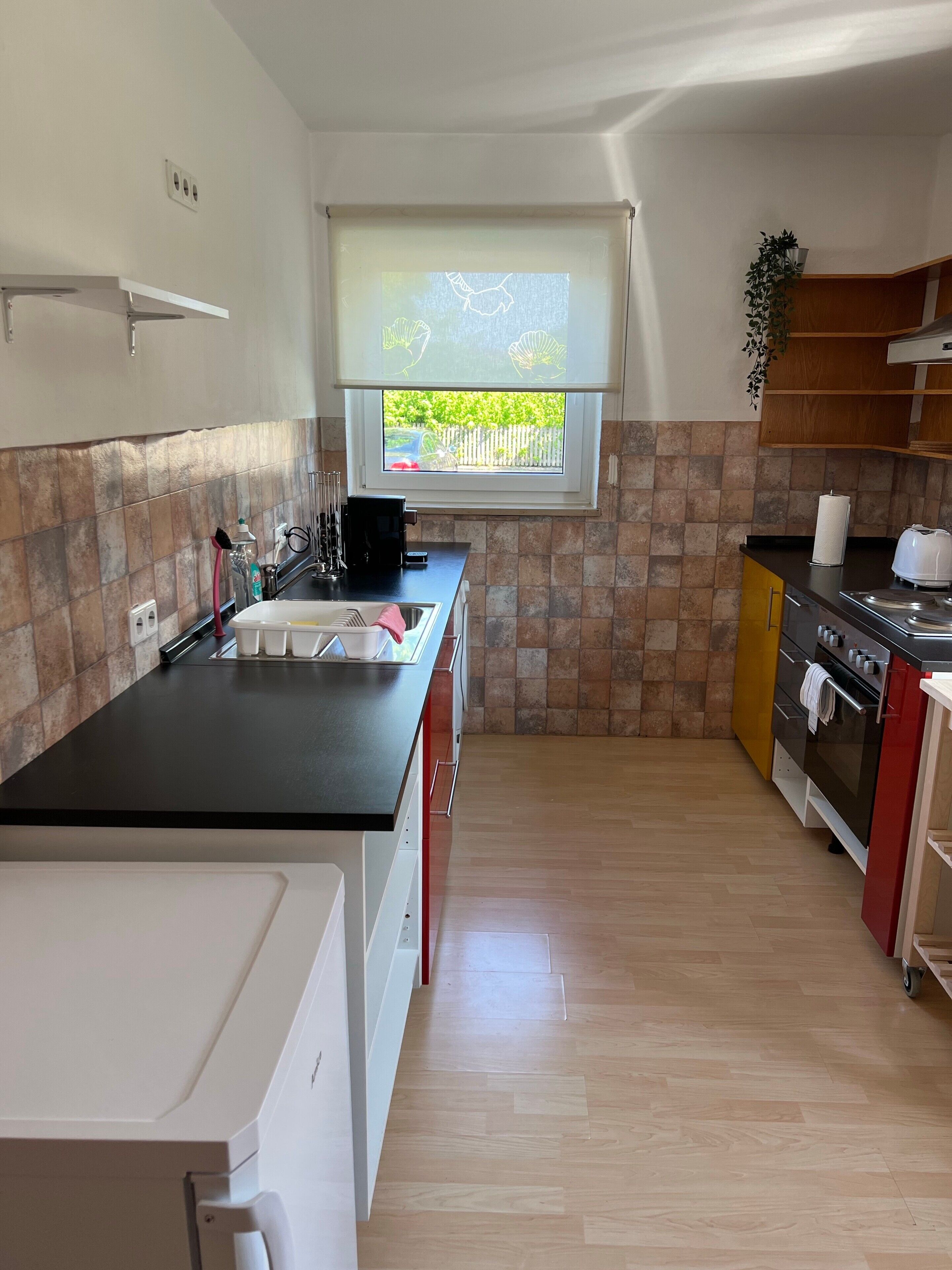 Uma cozinha compacta com janela, pia, fogão e bancada.