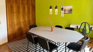 Una sala conferenze con un grande tavolo, sedie, un vaso con fiori e un quadro appeso al muro.