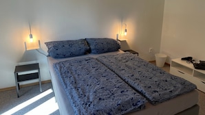 Una camera da letto con un letto, due comodini, un tavolino e una lampada a parete.
