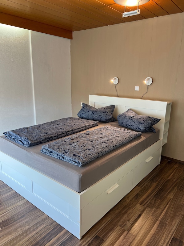 A neatly made bed with patterned bedding, a white headboard, and bedside lamps.
