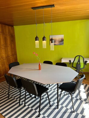 A conference room with a round table, black chairs, a striped rug, and pendant lights.