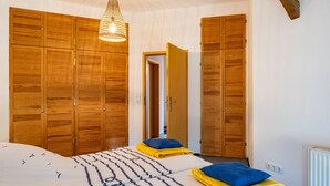 Une chambre avec des armoires en bois, un lit avec une literie à motifs et un luminaire suspendu.