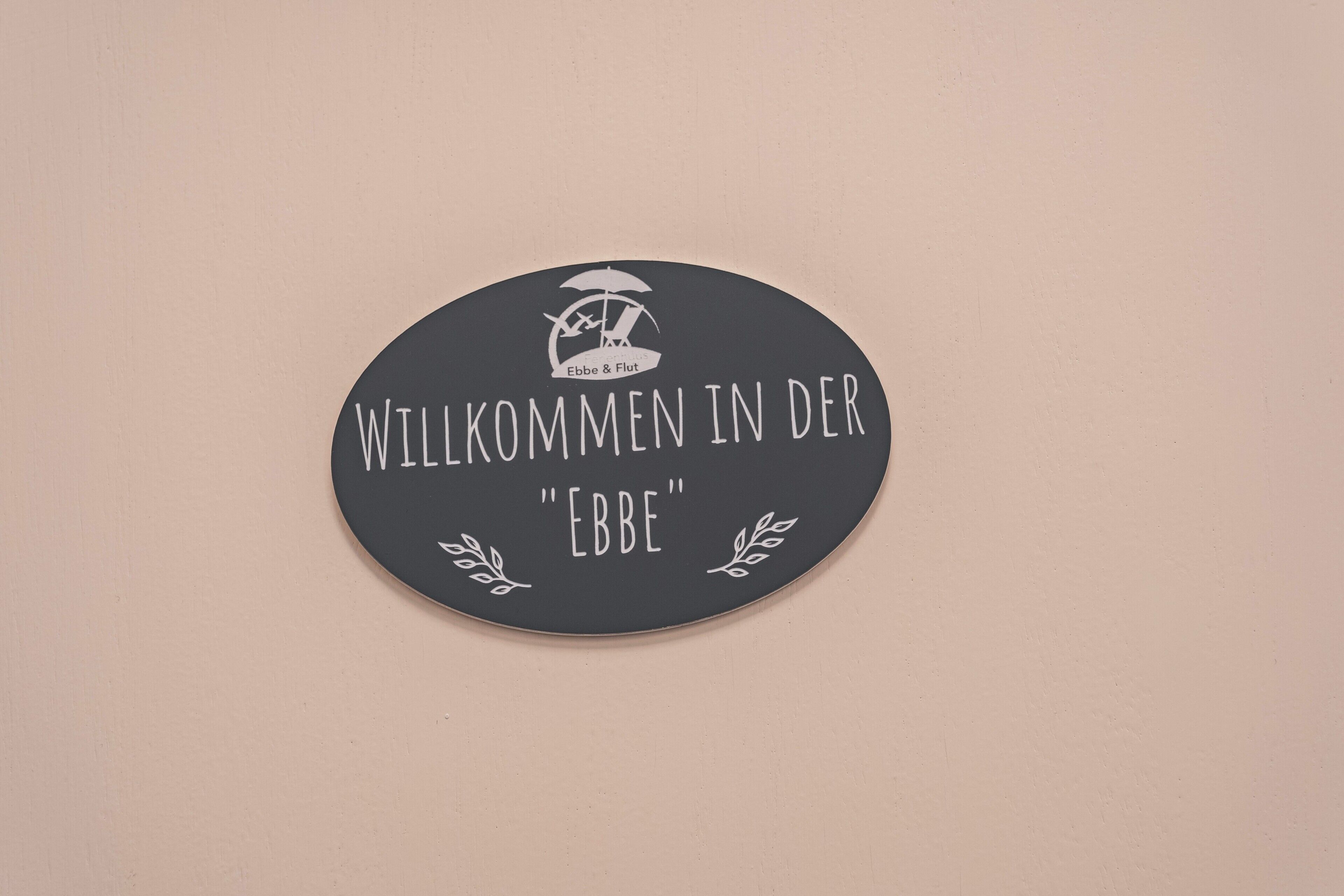 Ein rundes Schild mit der Aufschrift 'WILLKOMMEN IN DER EBBE' und einem Logo darüber.