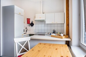 Une cuisine compacte avec des meubles blancs, une cuisinière encastrée et une petite table à manger.