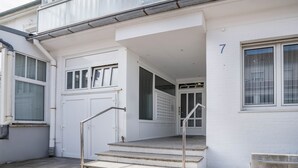 Entrada de um edifício com um conjunto de escadas, uma porta e uma janela marcada com o número 7.